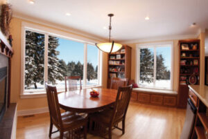 A dining room featuring beautiful windows overlooking a snowy day